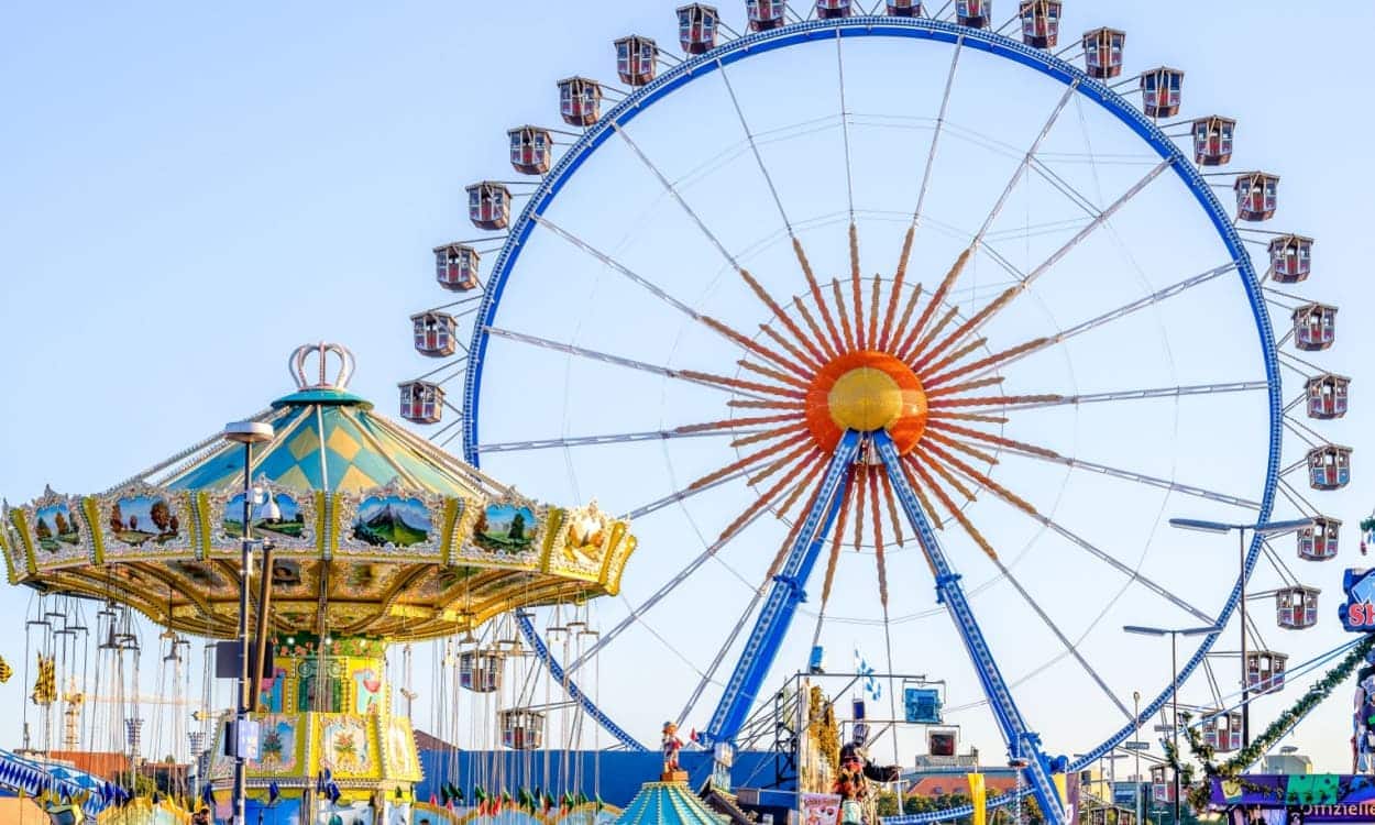 Imagem mostra uma roda gigante e um carrossel em um paque de diversões.