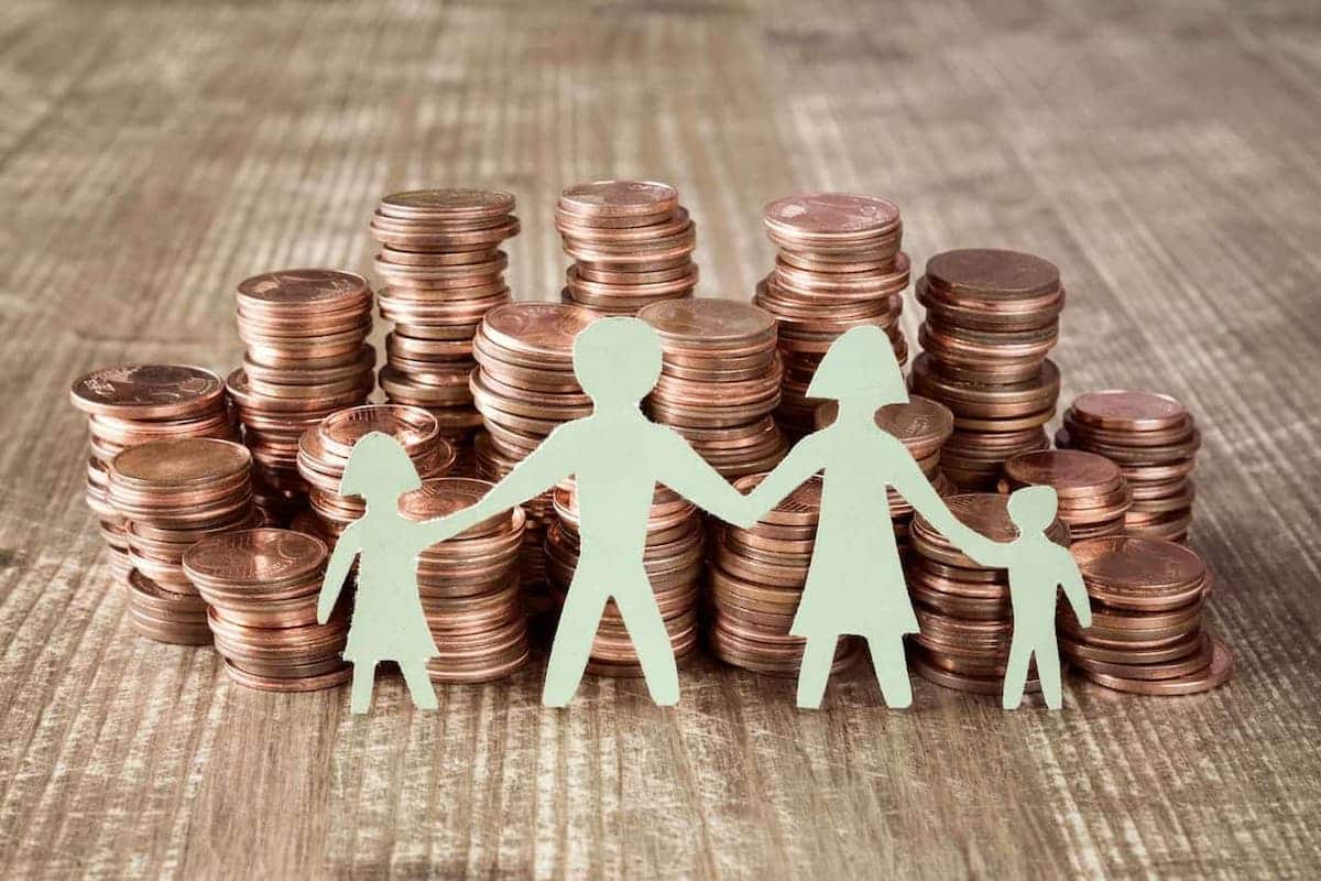 Família de papel com pilhas de moedas atrás