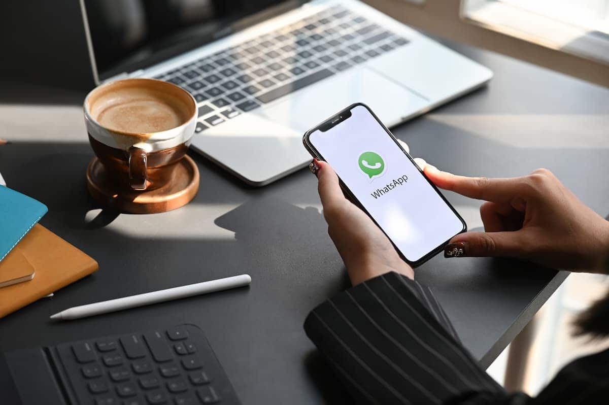 Aplicativo do Whatsapp aberto em Smartphone com usuário apoiando as mãos sobre a mesa de trabalho