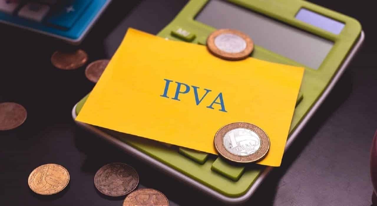 Imagem de um cartão com a sigla IPVA sobre uma calculadora e várias moedas. IPVA placas