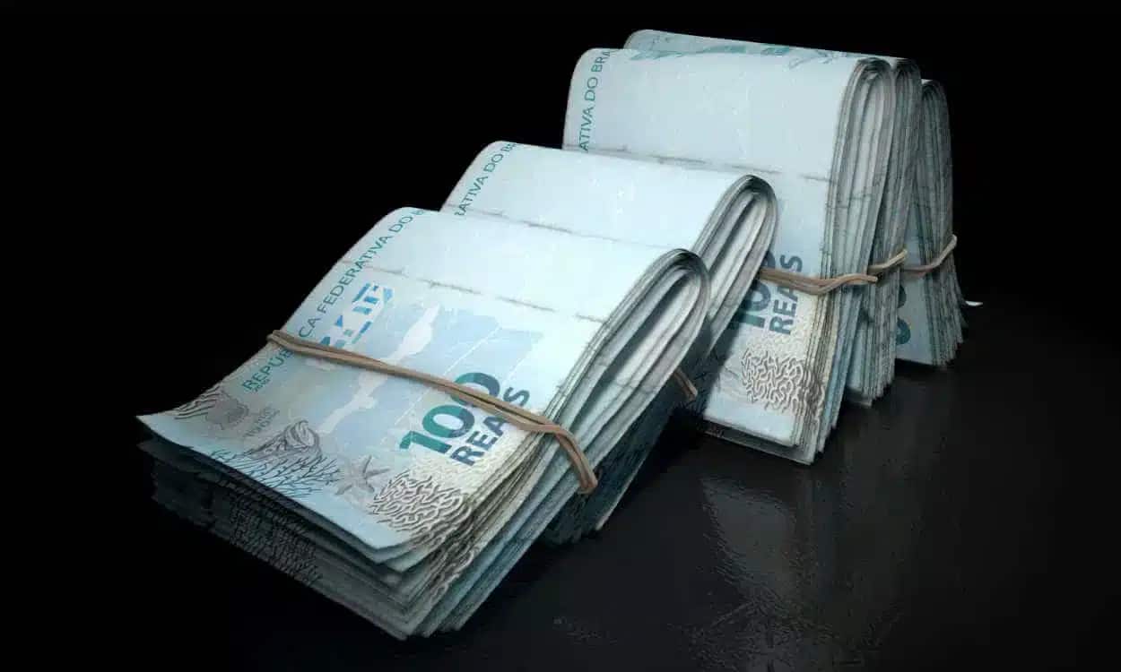 Conjuntos de notas de R$ 100 presas com elástico e apoiadas um nos outros representando R$ 1 milhão