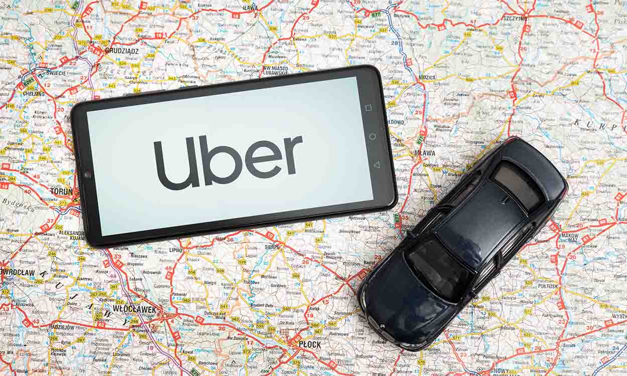 Miniatura de carro e celular com logo do uber em cima de um mapa