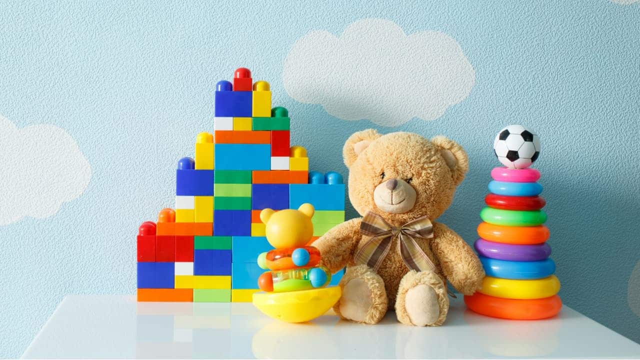 Blocos montar, anéis empilháveis com uma bola de futebol, urso de pelúcia e pequeno brinquedo de plástico.