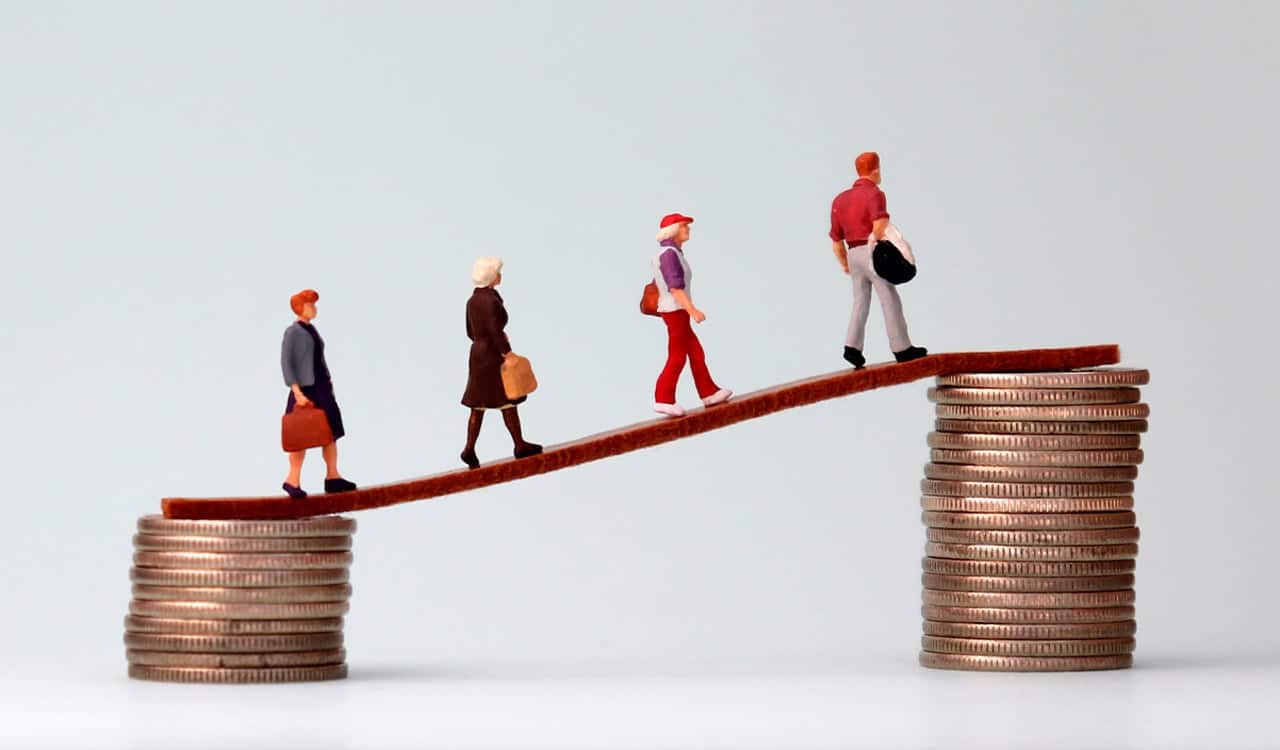 Miniatura de pessoas subindo uma rampa equilibrada por moedas
