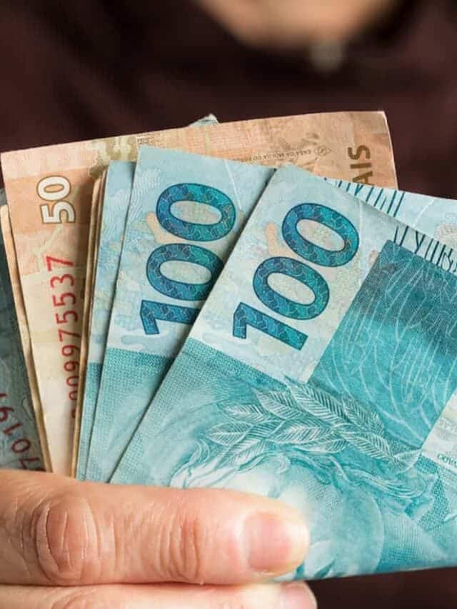Mão segurando dinheiro, em notas de 50 e 100 reais representando novo auxílio de R$ 900