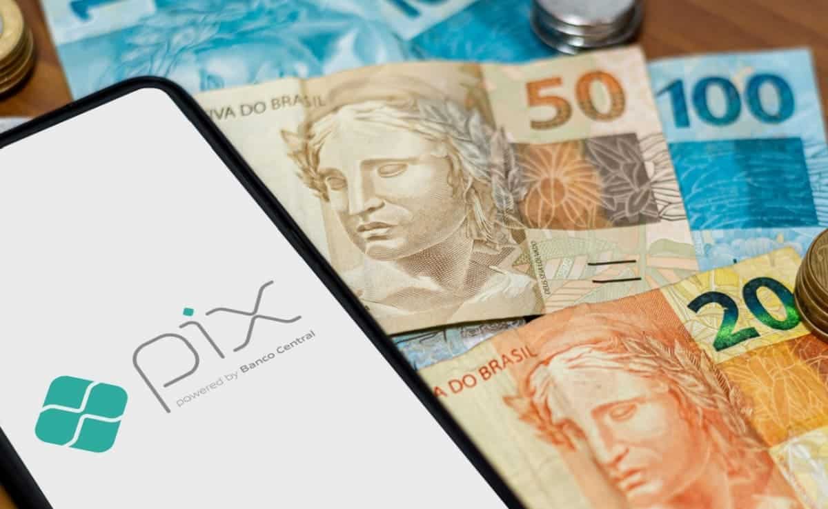 Celular com a logo do PIX na tela por cima de notas de Real