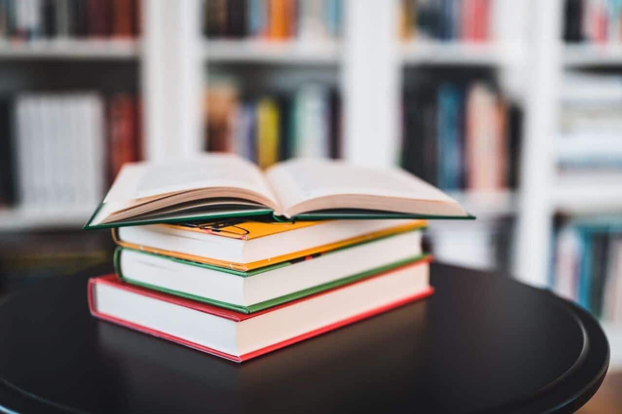 Quatros livros de capas coloridas sobre investir empilhados sobre uma mesa preta. analfabetismo profesores