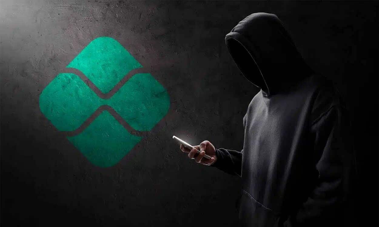 Na imagem, homem encapuzado com celular na mão em fundo preto com símbolo do PIX.