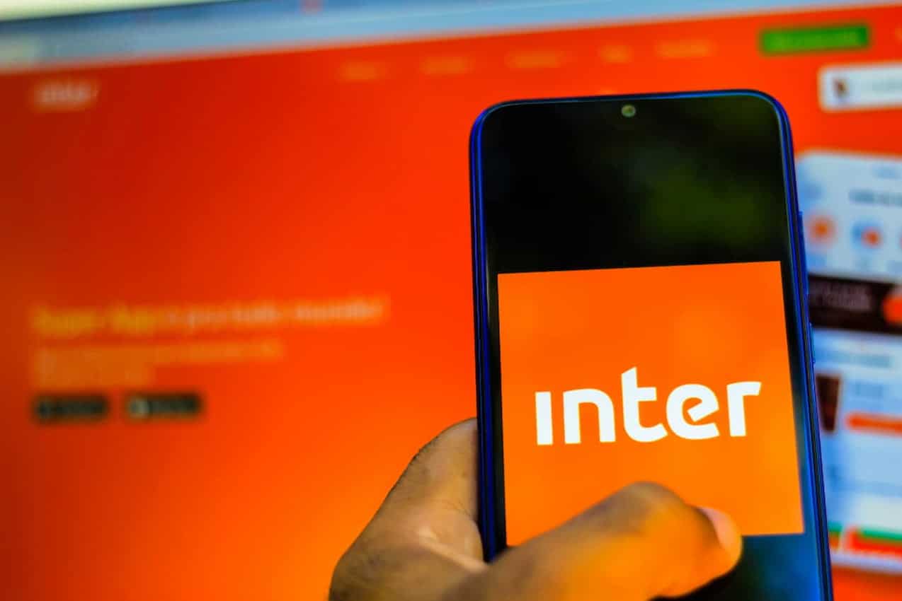 Mão segurando celular com app do Inter aberto.