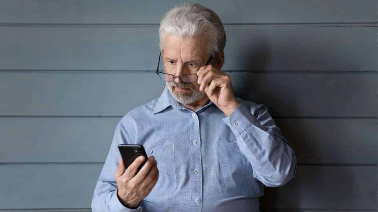 Idoso olhando desconfiado para o celular