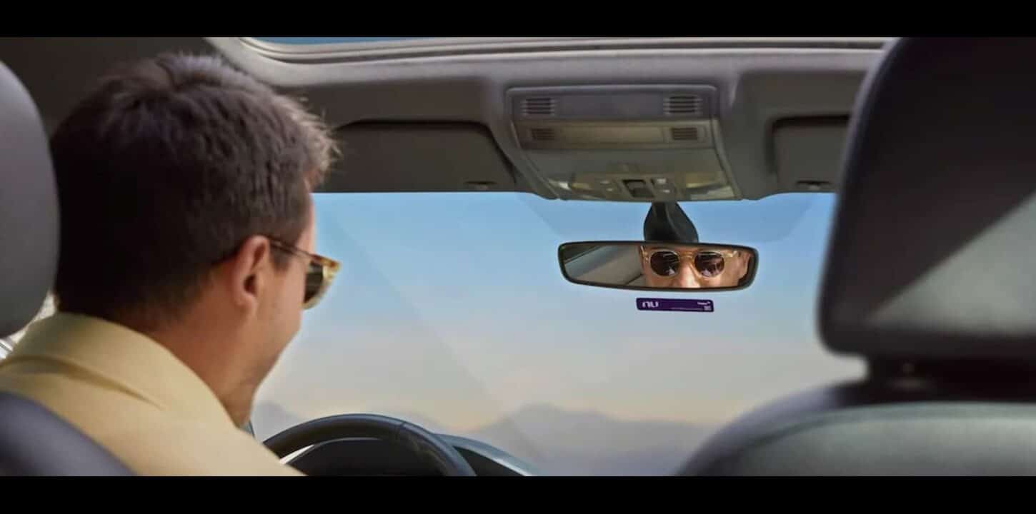 Imagem de um homem dentro de um carro, com a NuTag do Nubank.