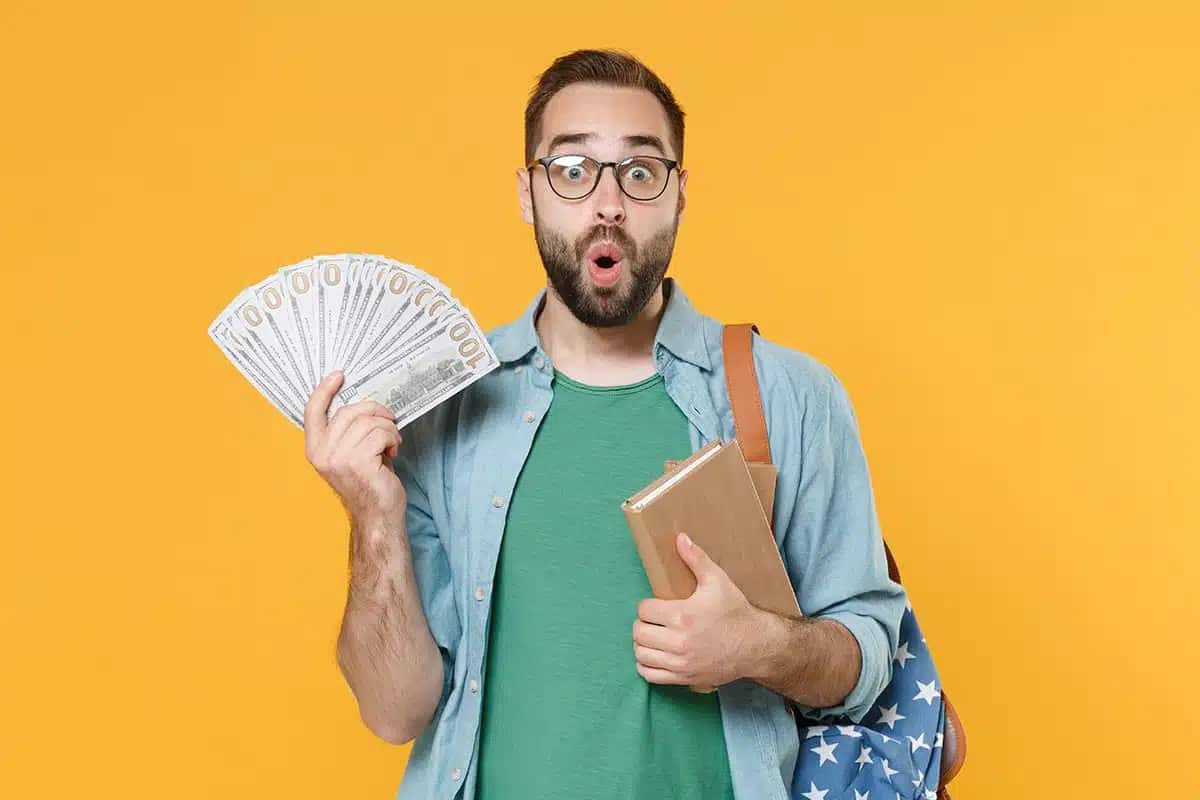 Estudante universitário de programa do governo em choque com grande quantia de dinheiro nas mãos.