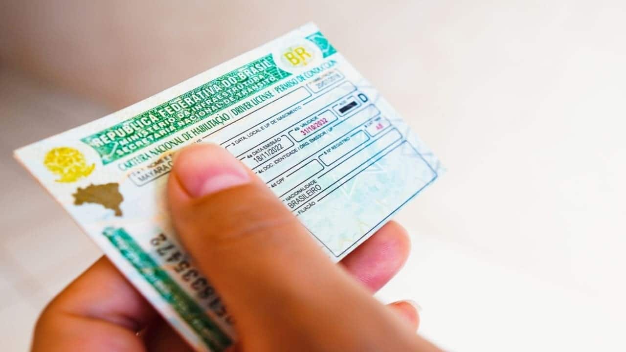 Mão feminina segurando Carteira Nacional de Trânsito