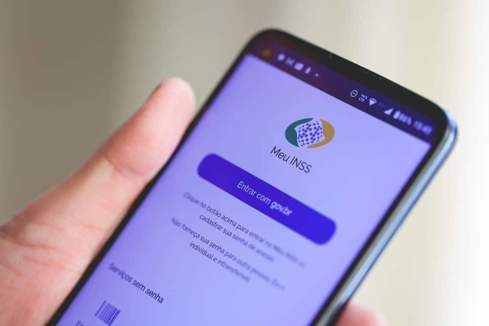 Pessoa segurando celular com aplicativo "Meu INSS" aberto