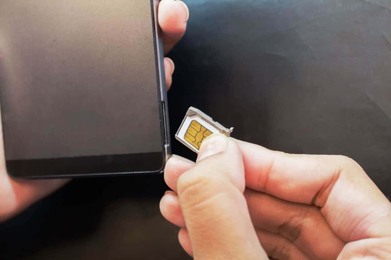 Mão inserindo um chip em um aparelho.