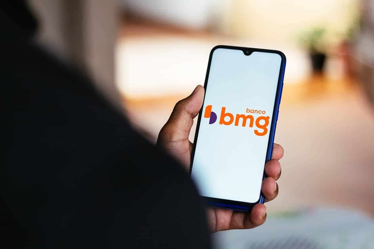 Celular com aplicativo do banco BMG na tela inicial.