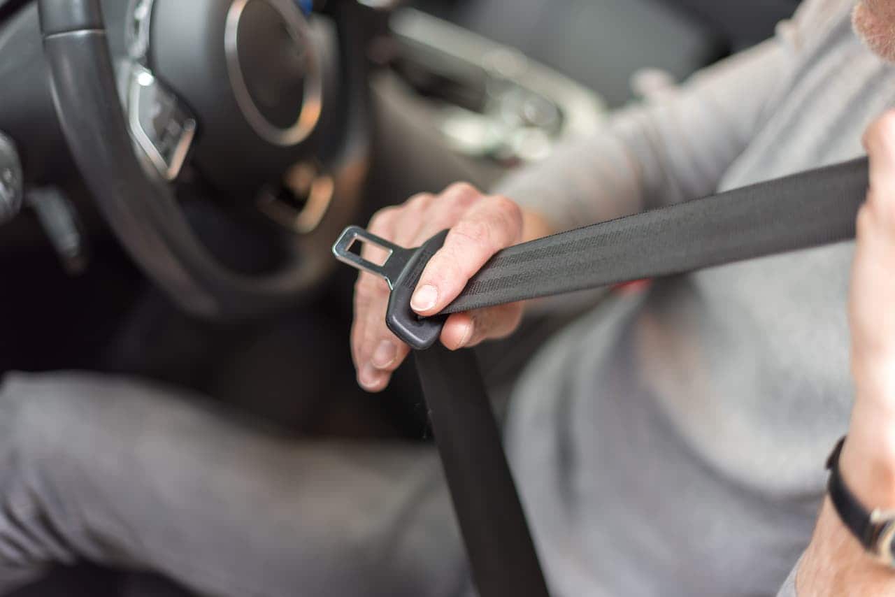 homem colocando cinto de segurança em carro