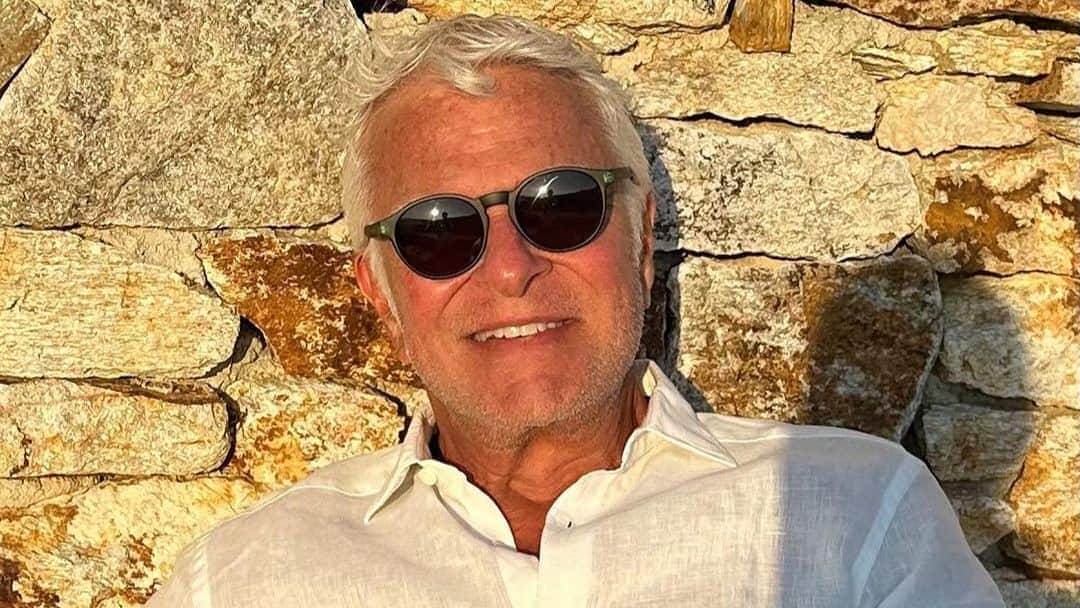 O empresário Fernando Alterio, dono da T4F, sorrindo, com uma camisa branca e de óculos de sol. Ele é um homem grisalho de 71 anos.