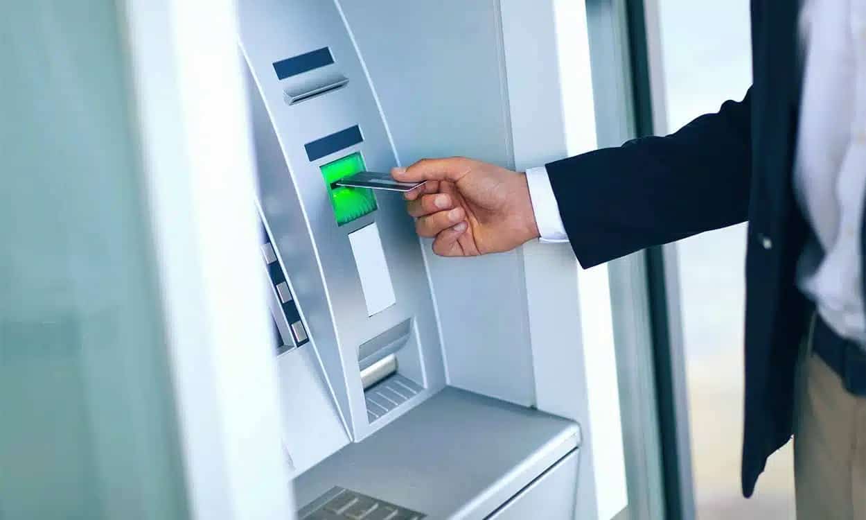 Pessoa colocando o cartão no caixa eletrônico do banco.
