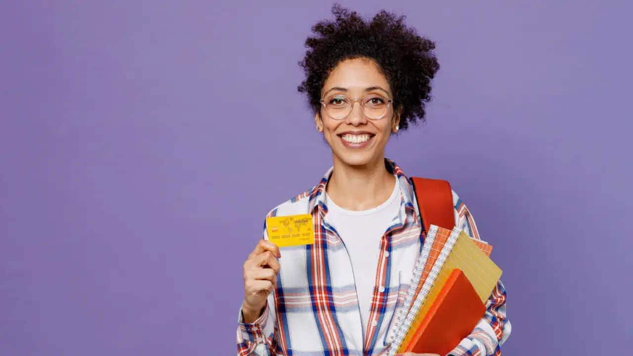 Estudante segurando livros e um cartão