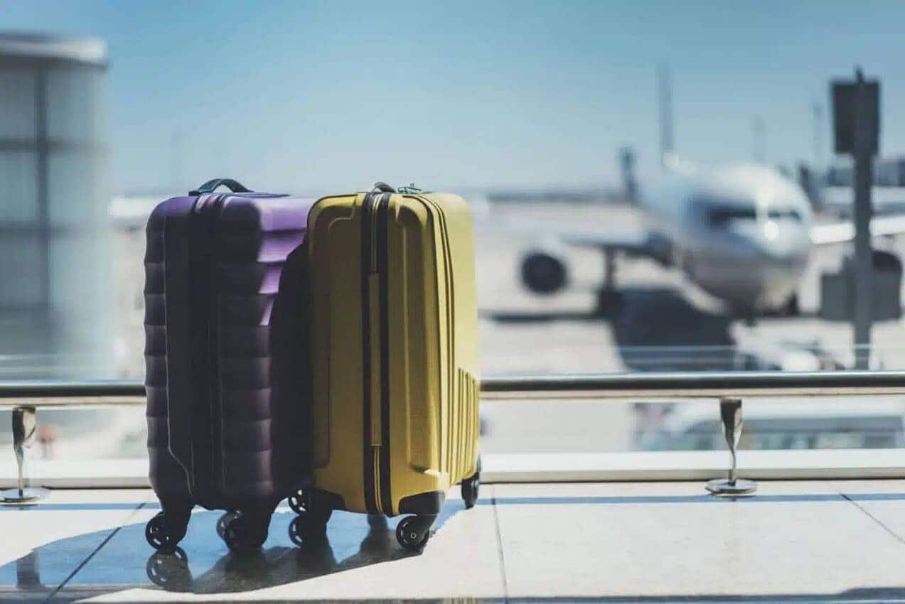 malas de viagem em aeroporto e um avião decolando ao fundo
