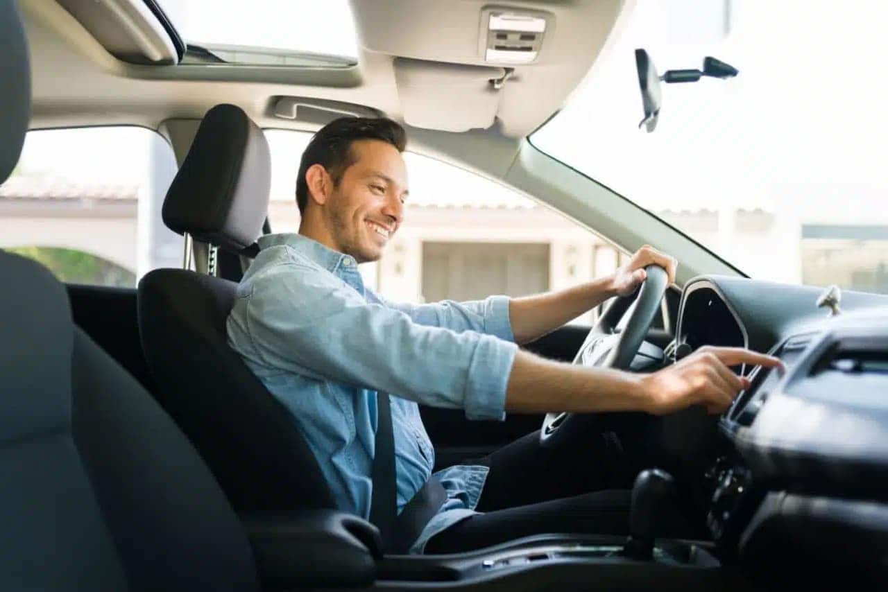 Homem sorrindo enquanto dirige carro