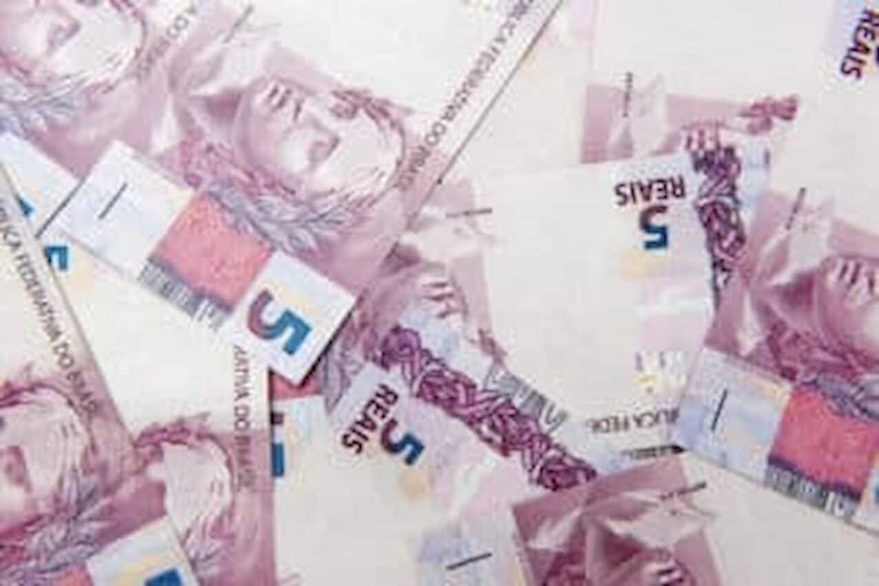 Imagem de várias notas de dinheiro de R$ 5 espalhadas