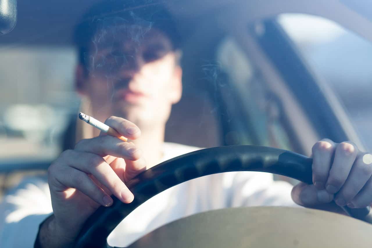 Homem fumando no volante