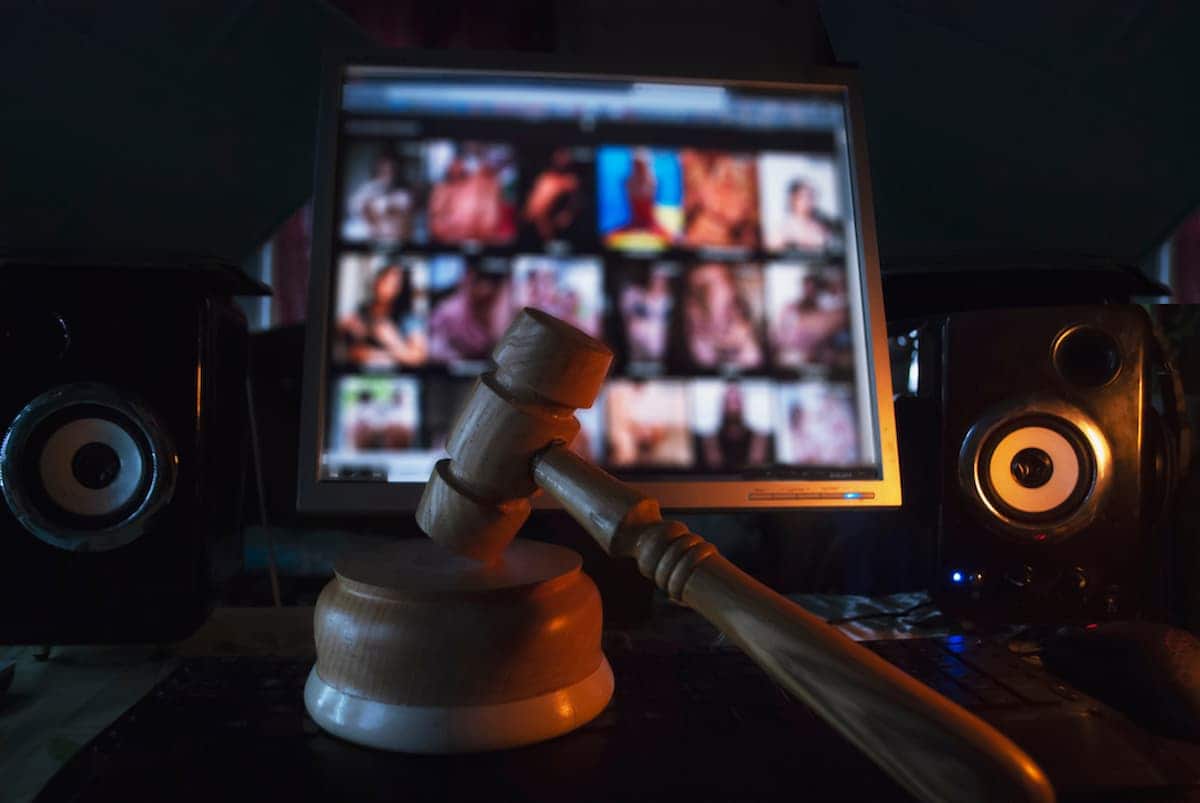 Martele na frente da tela de um computador, que exibe um site com conteúdo adulto
