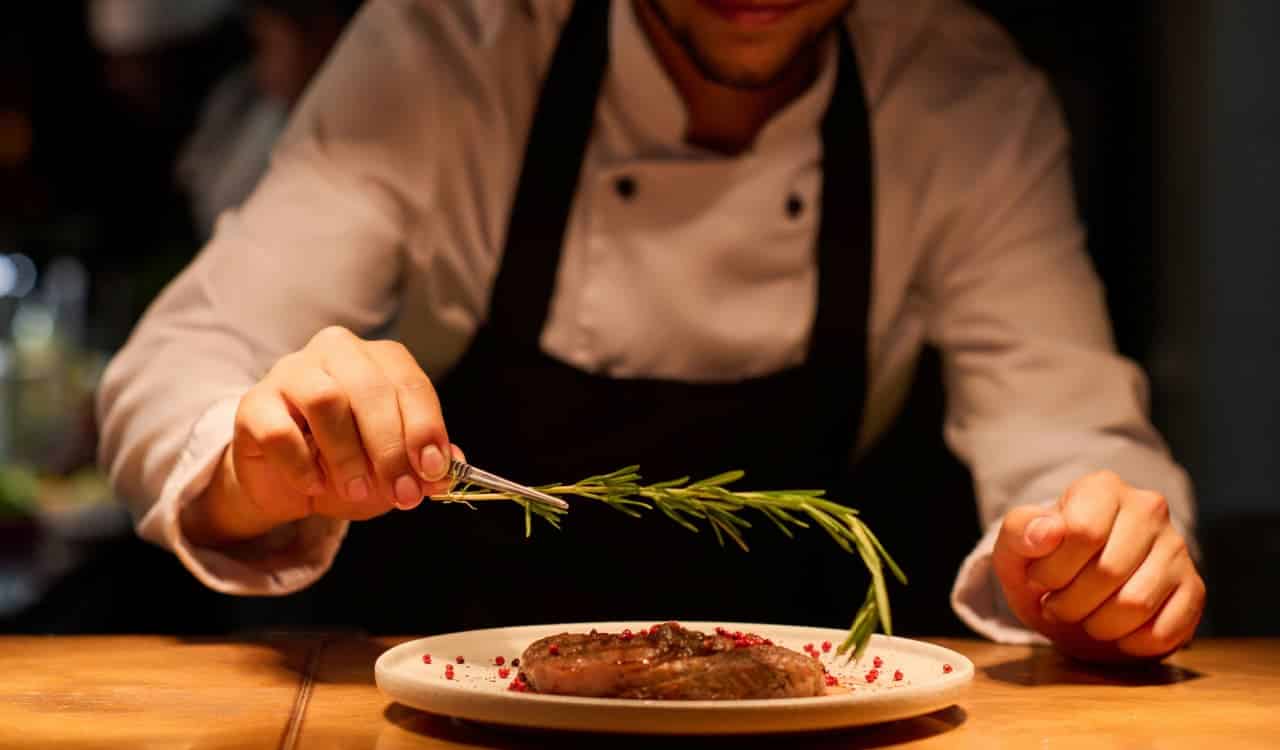 Chef de cozinha finalizando montagem de prato em restaurante