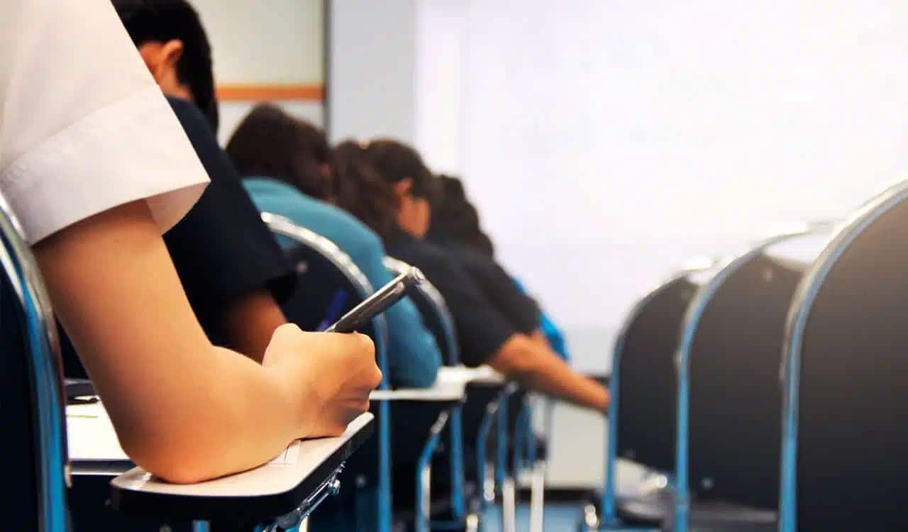 Pessoas sentadas em sala de aula fazendo a prova de concurso