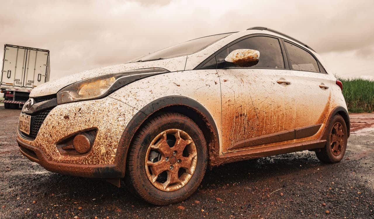 Carro branco muito sujo de barro