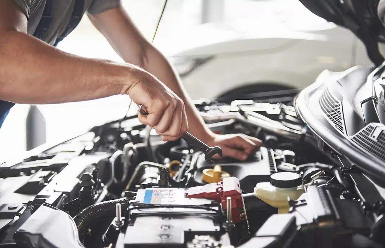 Homem com uma chave inglesa para arrumar o motor de um carro na oficina mecânica