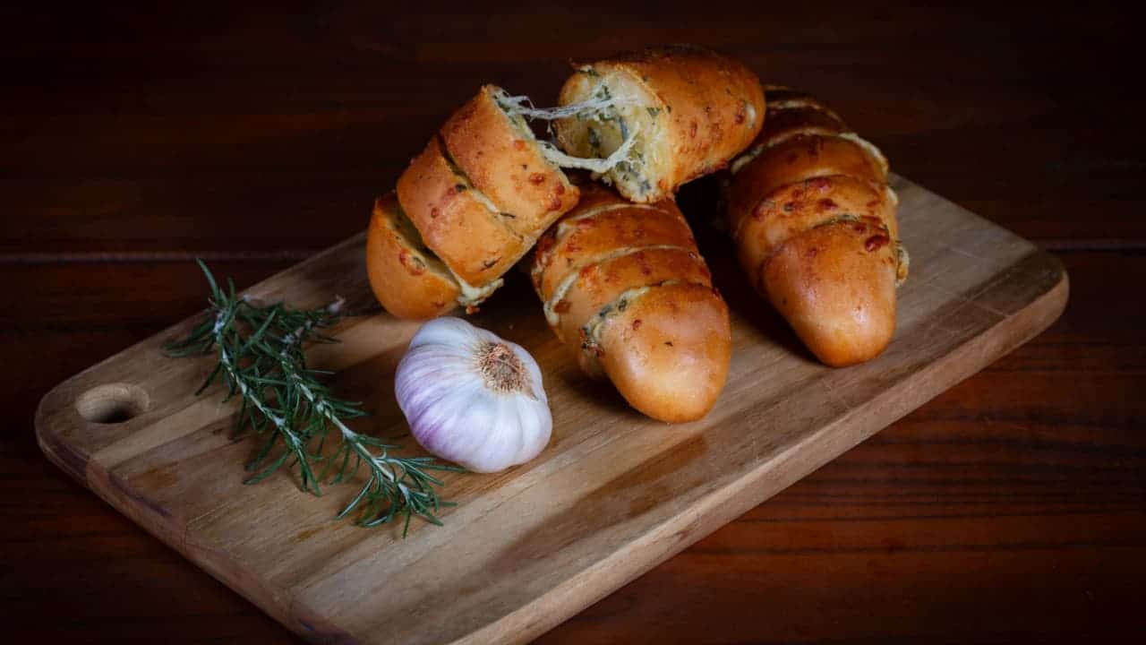 Pão de alho assado em cima de uma tábua de madeira
