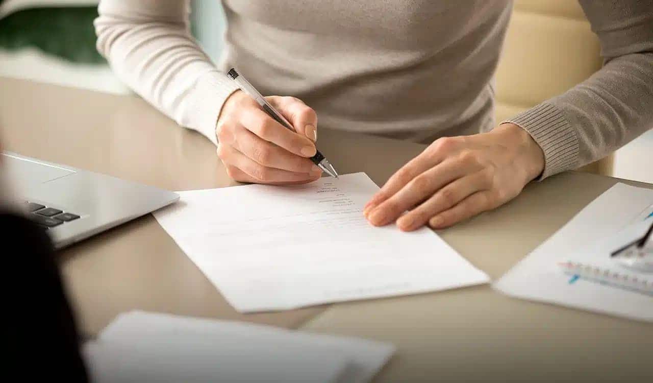 Imagem de uma pessoa assinando um papel, fazendo alusão ao atestado médico