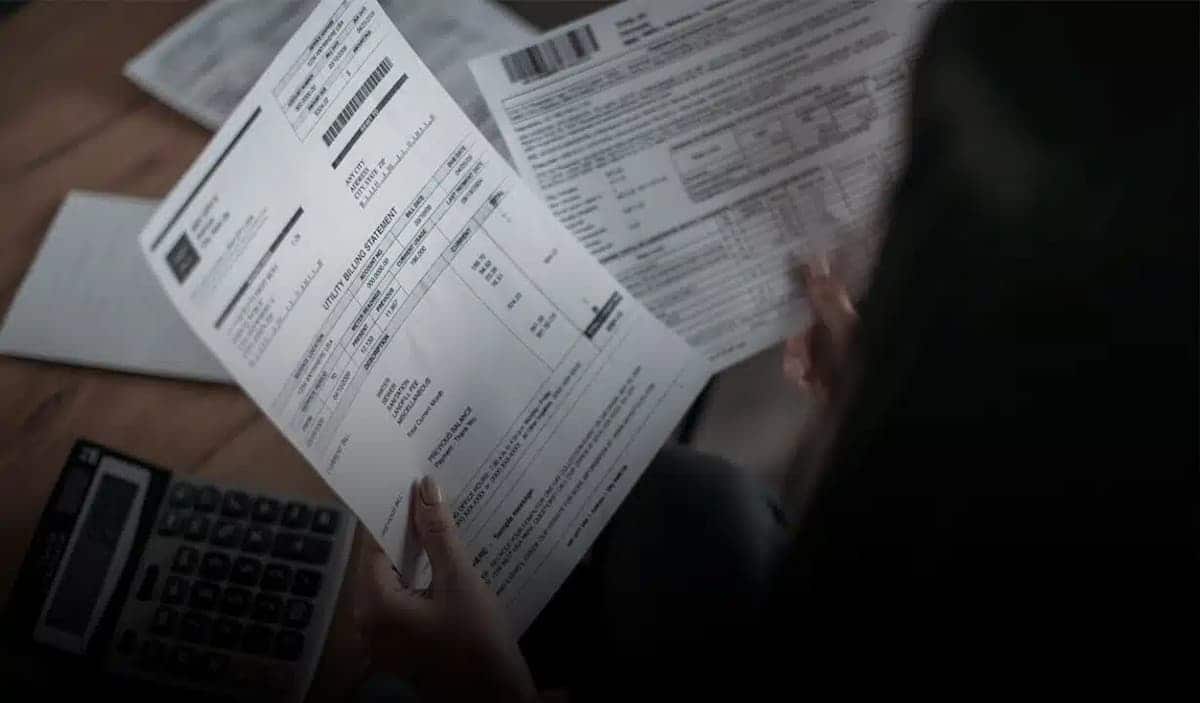 Pessoa segurando contas simulando comprovante de residência.