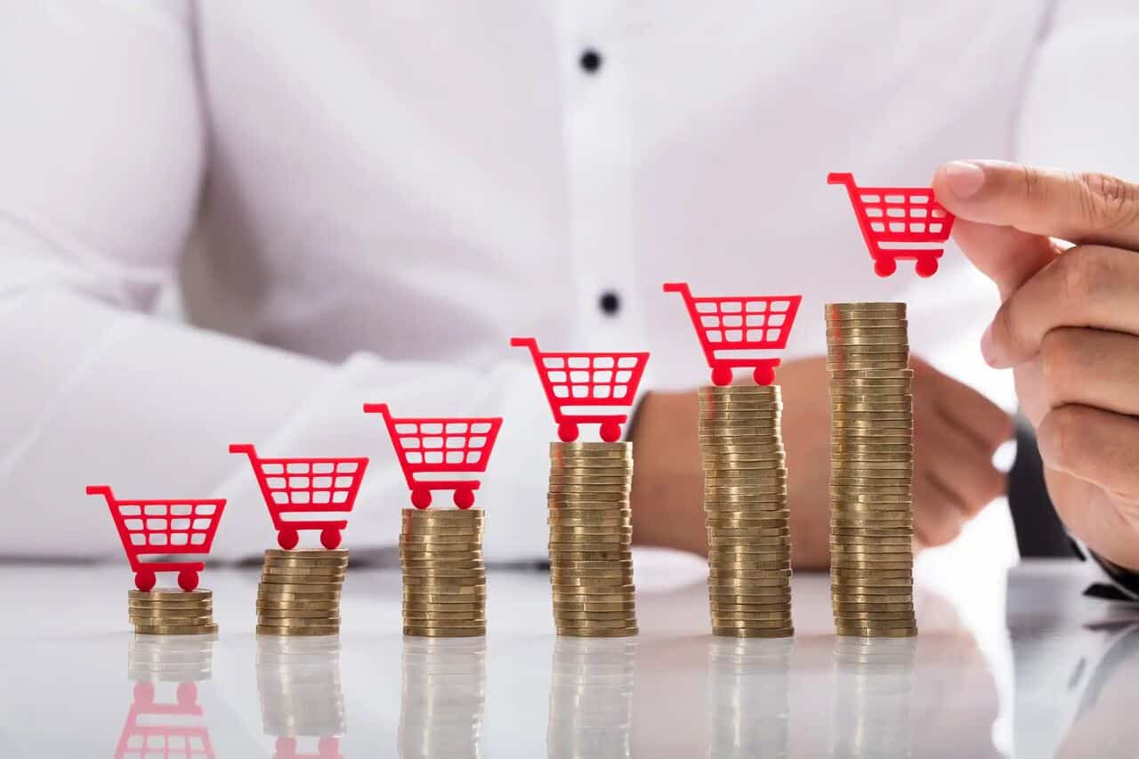 Pilhas de moedas em ordem crescente com carrinhos de compra vermelhos em cima