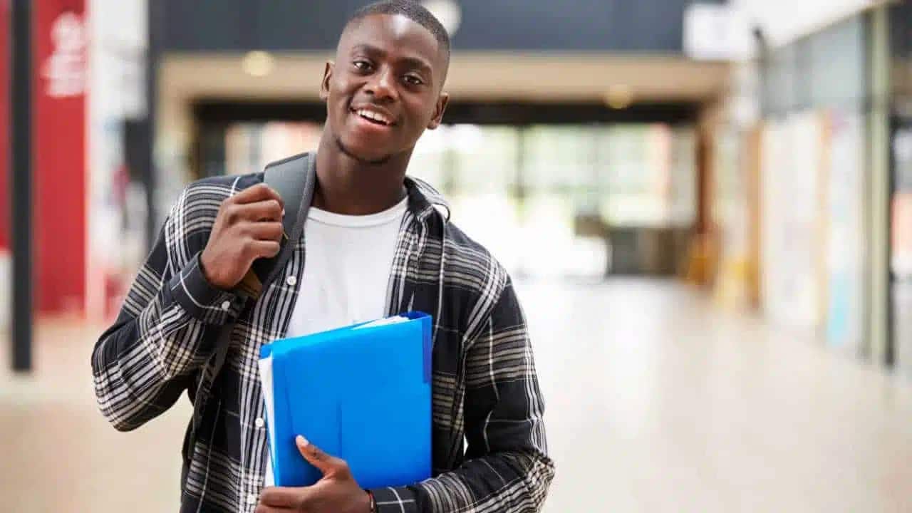 Estudante com mochila nas costas e segurando um fichário.
