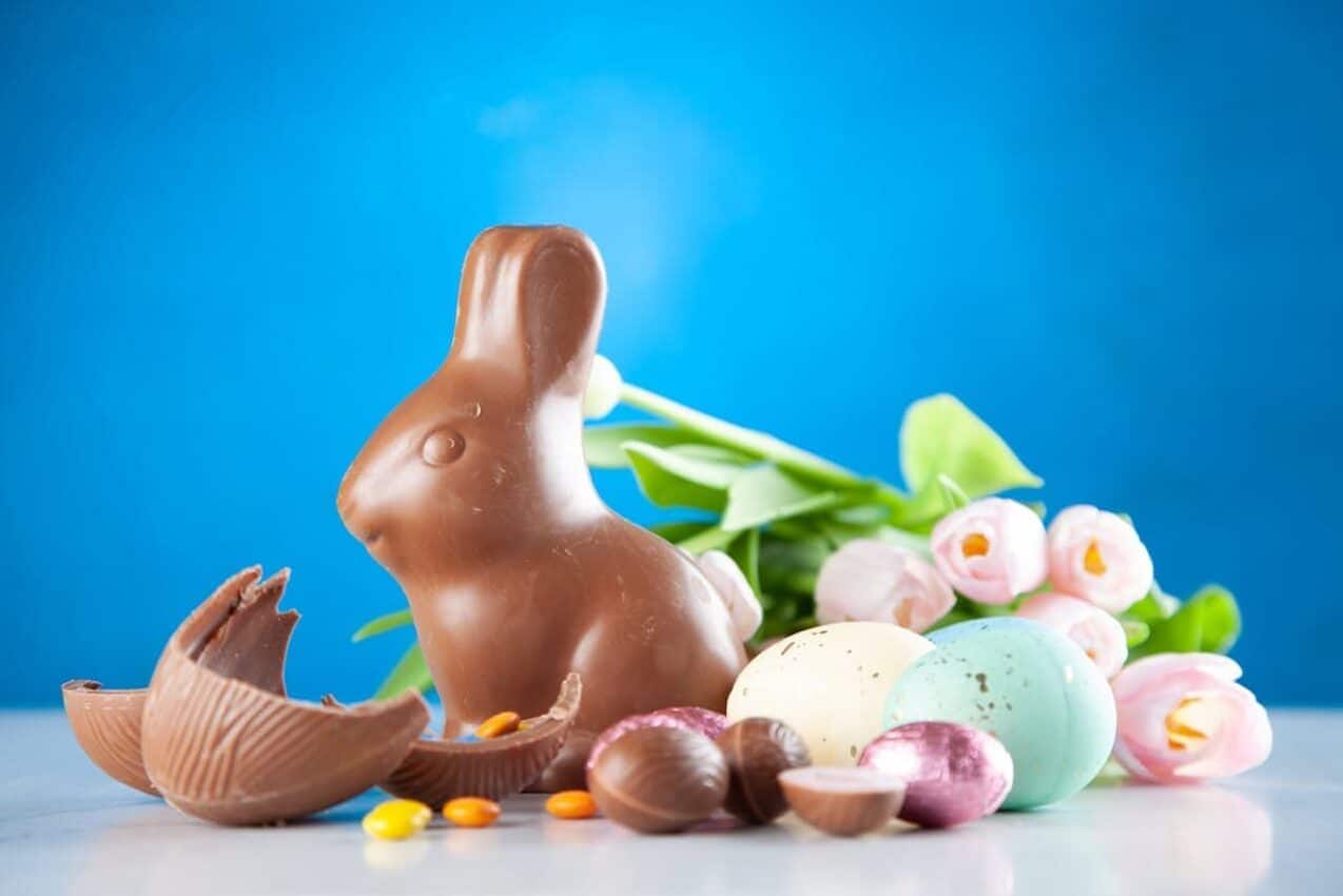 Coelho de páscoa de chocolate juntamente com outros chocolates em cima de uma mesa