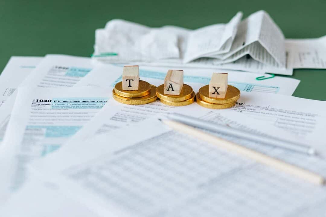 Dados em cima de moedas, formando a palavra taxa, com vários papéis em volta