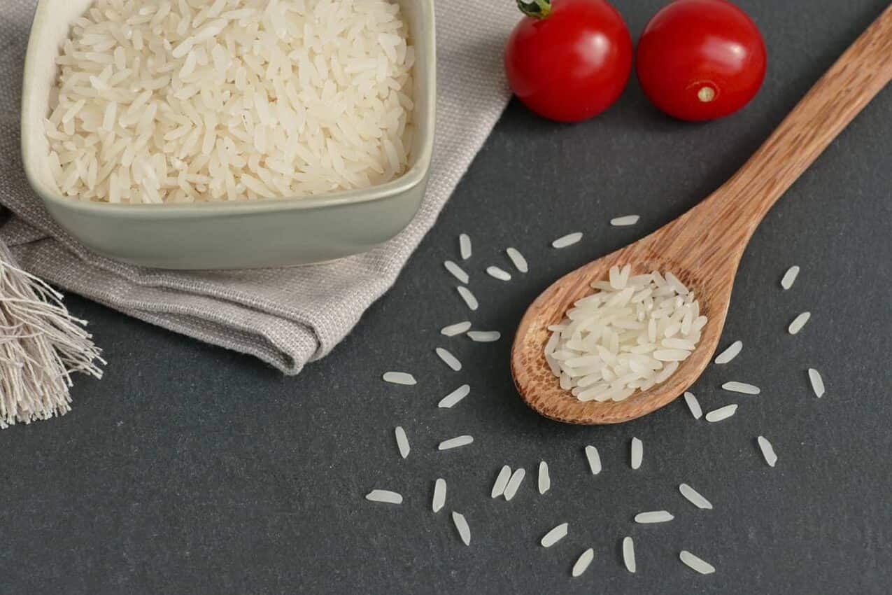 Imagem de uma tigela com arroz e ao lado uma colher de pau