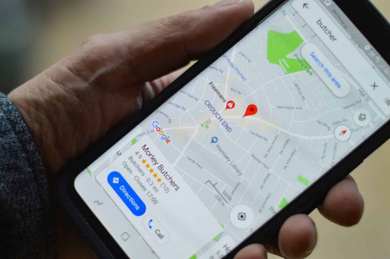 Uma mão segurando um celular com o mapa marcando uma localização