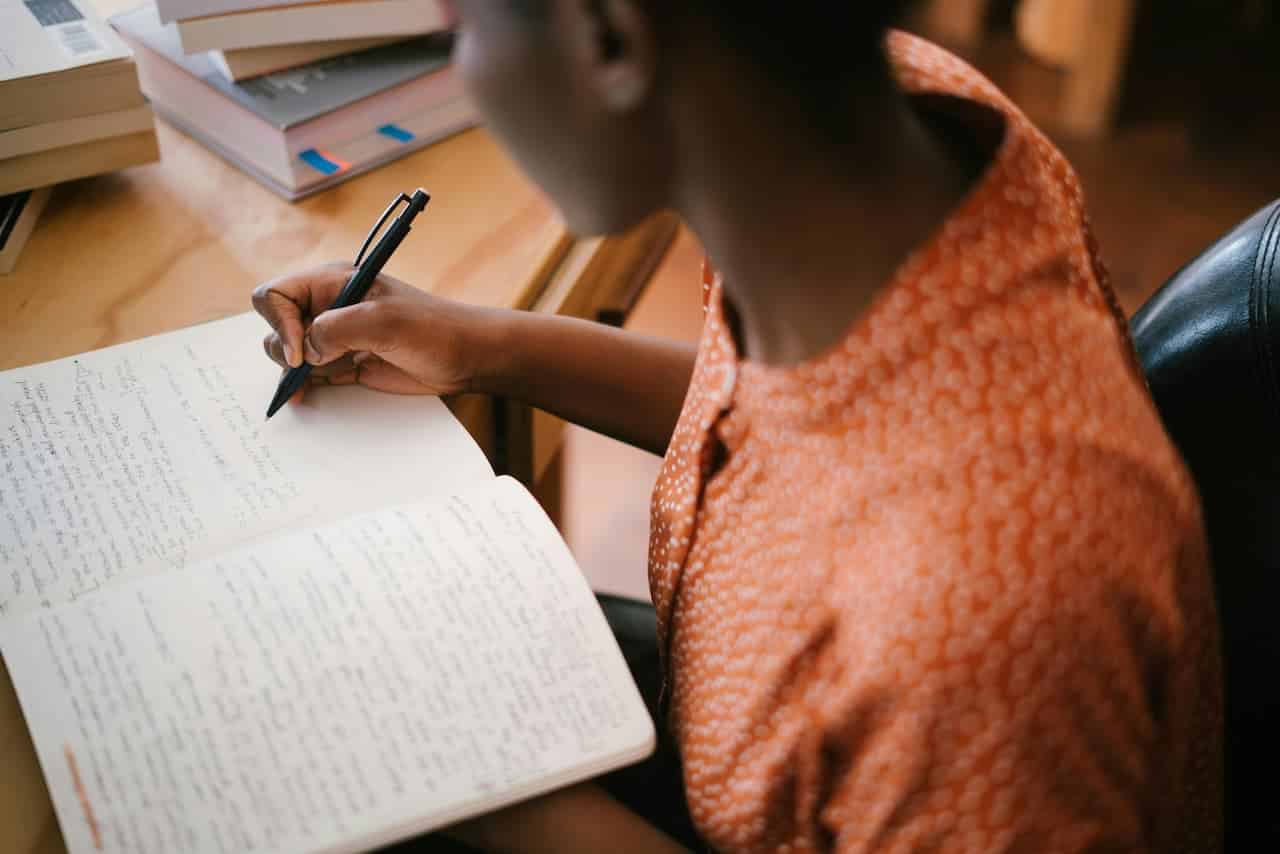 Imagem de uma mulher escrevendo em um caderno CNU