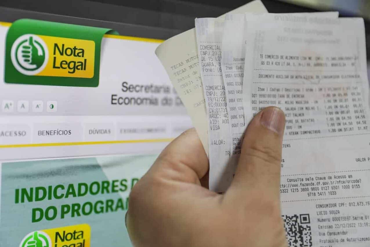 Uma mão segurando várias notais fiscais
