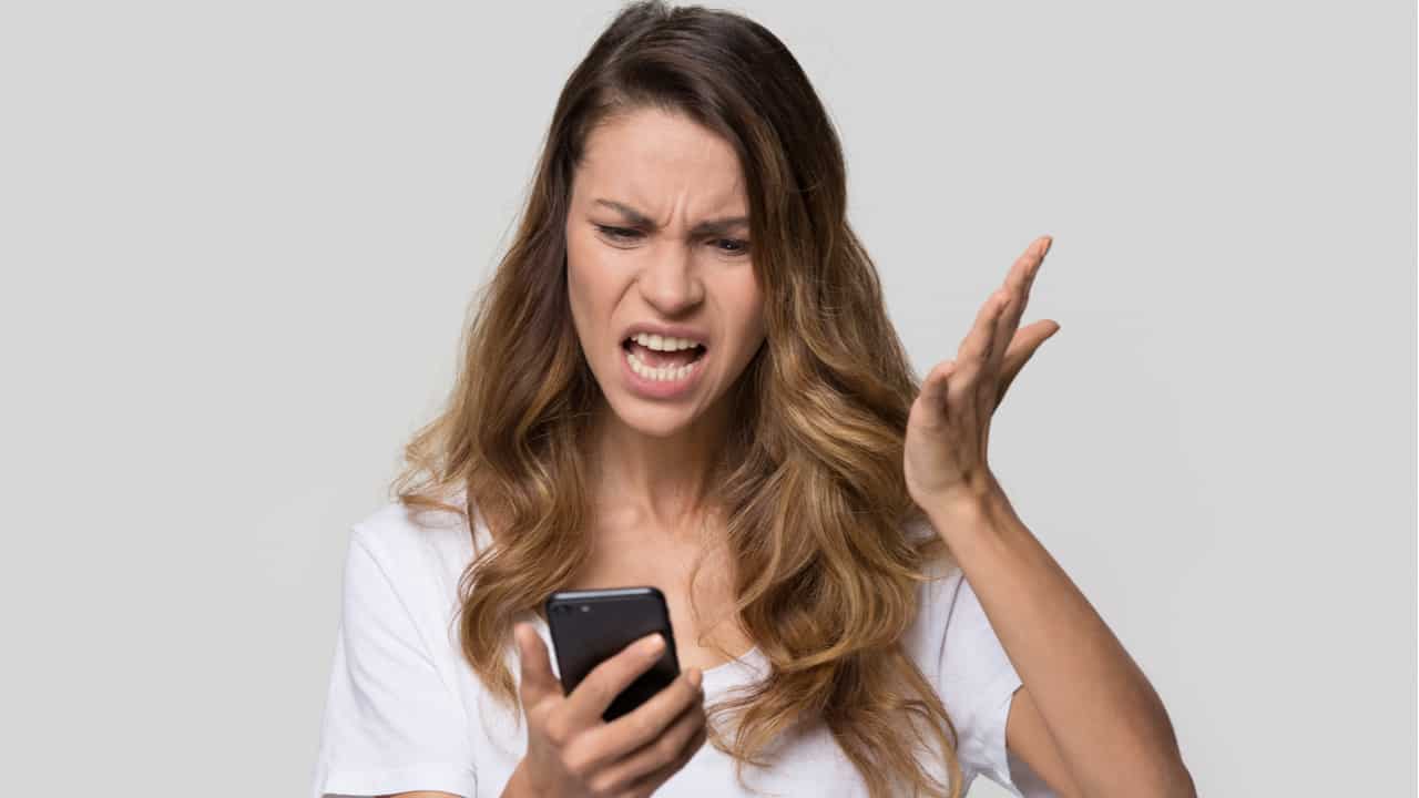 Mulher irritada com celular na mão