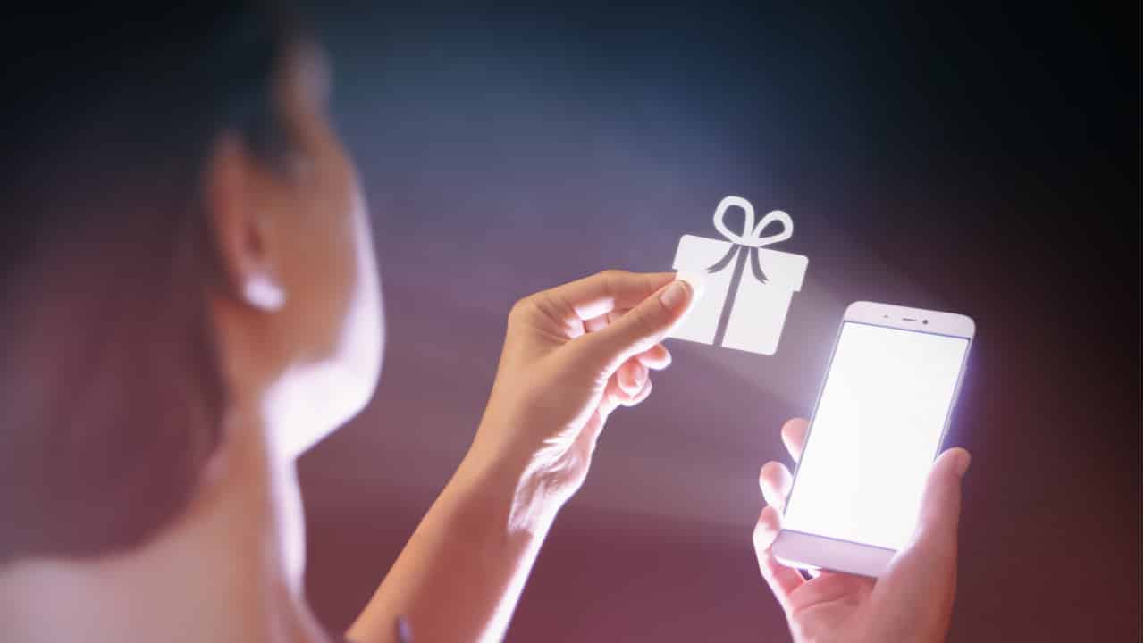 Pessoa usando a luz do smatphone para iluminar o ícone de presente