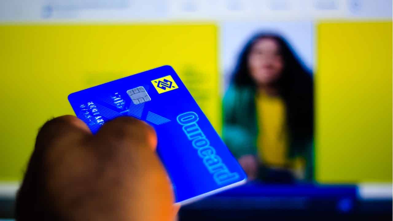 MĂŁo segurando cartĂŁo Ourocard do Banco do Brasil.