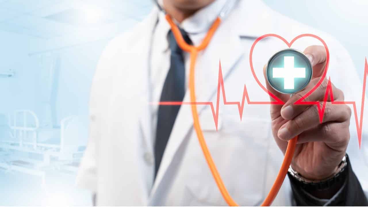 Médico segurando estetoscópio e uma ilustração à frente simbolizando os sinais vitais.