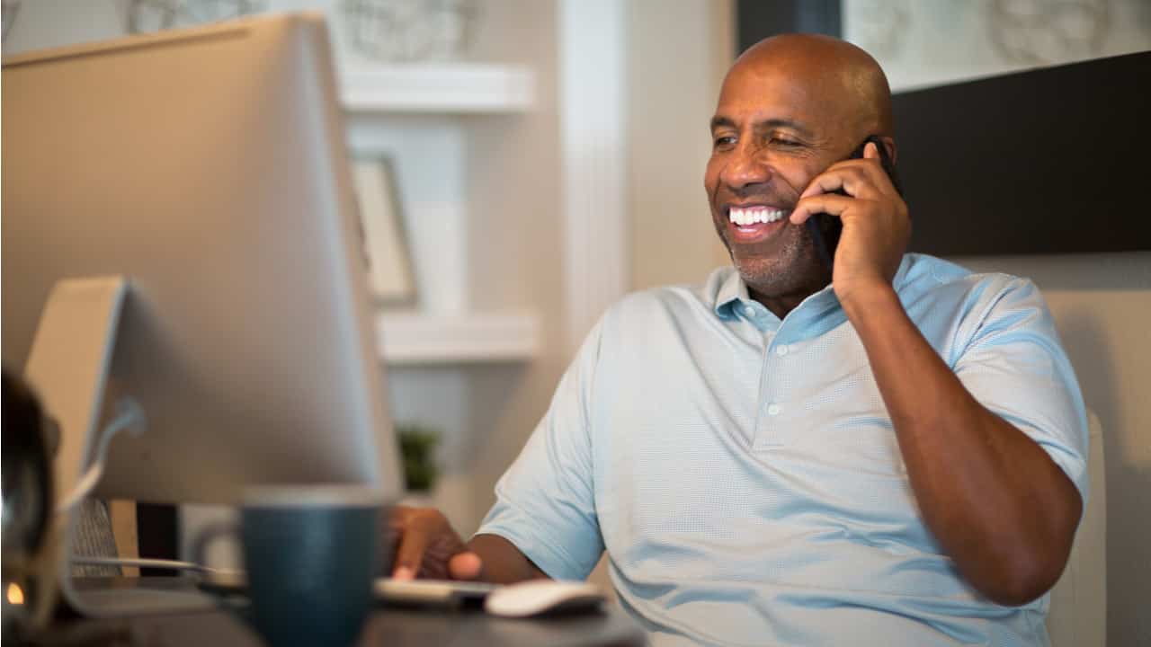 Homem negro falando ao telefone em mesa de escritório