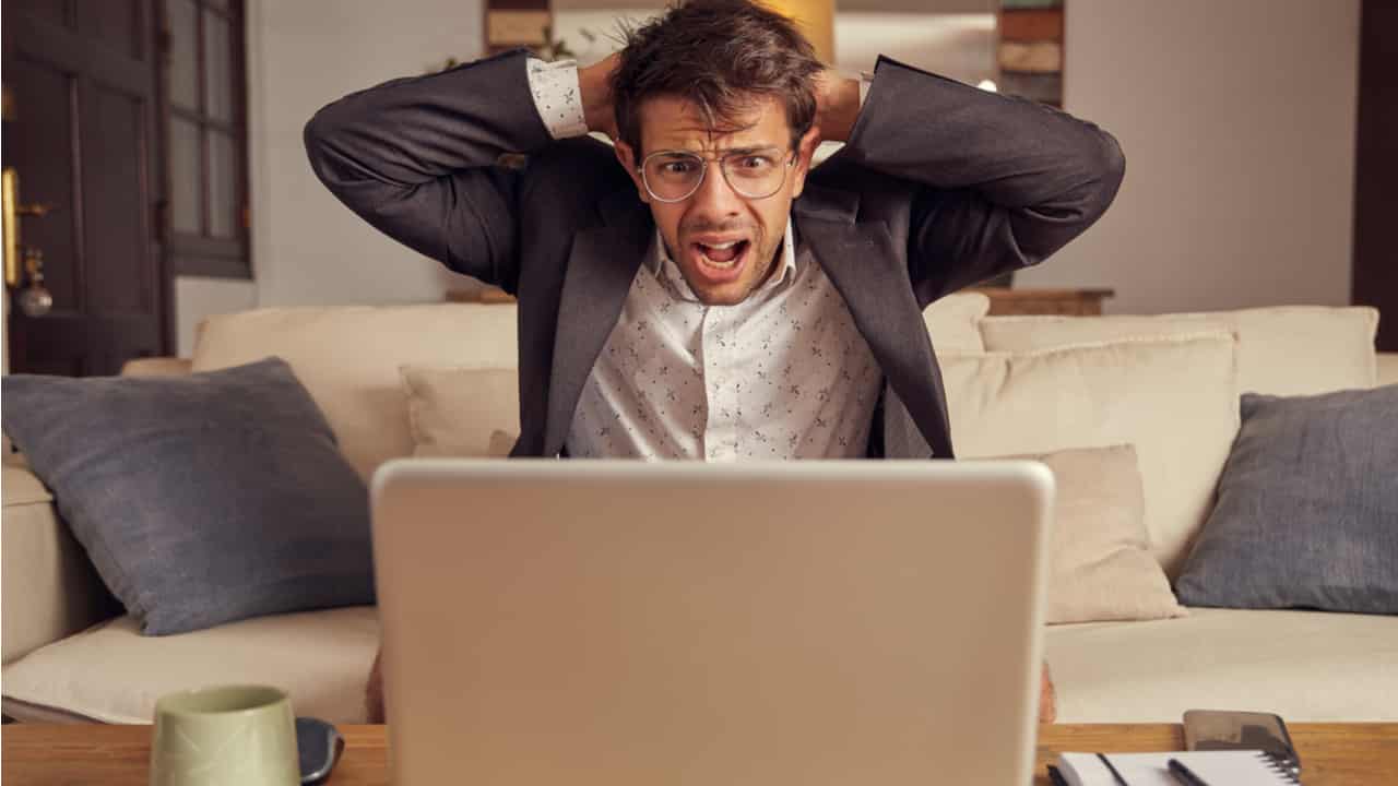 homem chocado coloca mãos na cabeça enquanto lê notícia no notebook